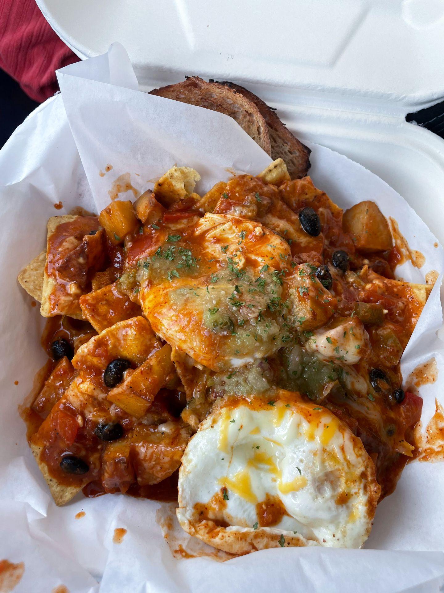 A plate of migas with sourdough toast in a to-go box from Stanley Baking Company & Café.