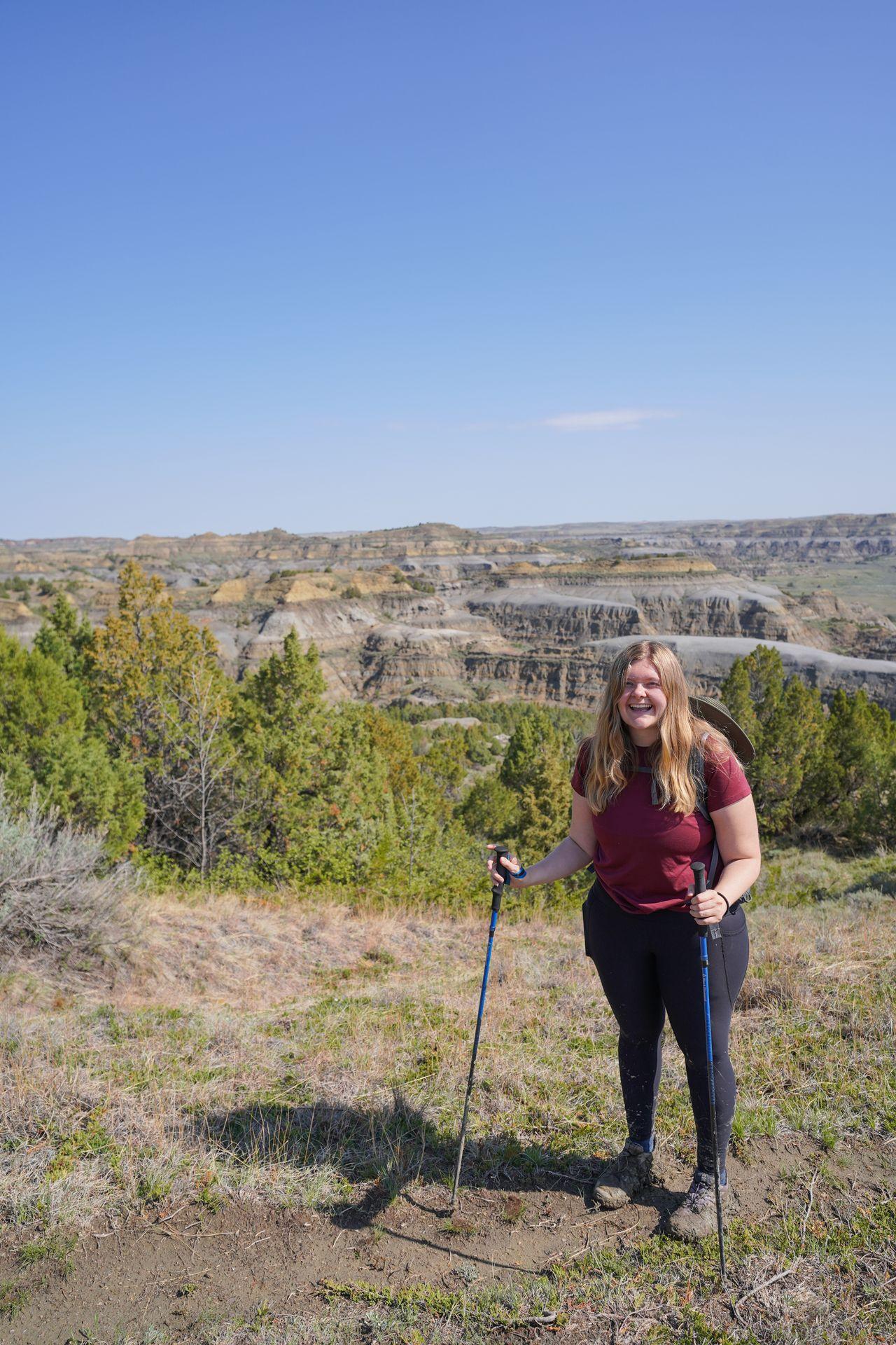 Lydia standing in front of a view with gray and yellow badlands on the Caprock Coulee Trail