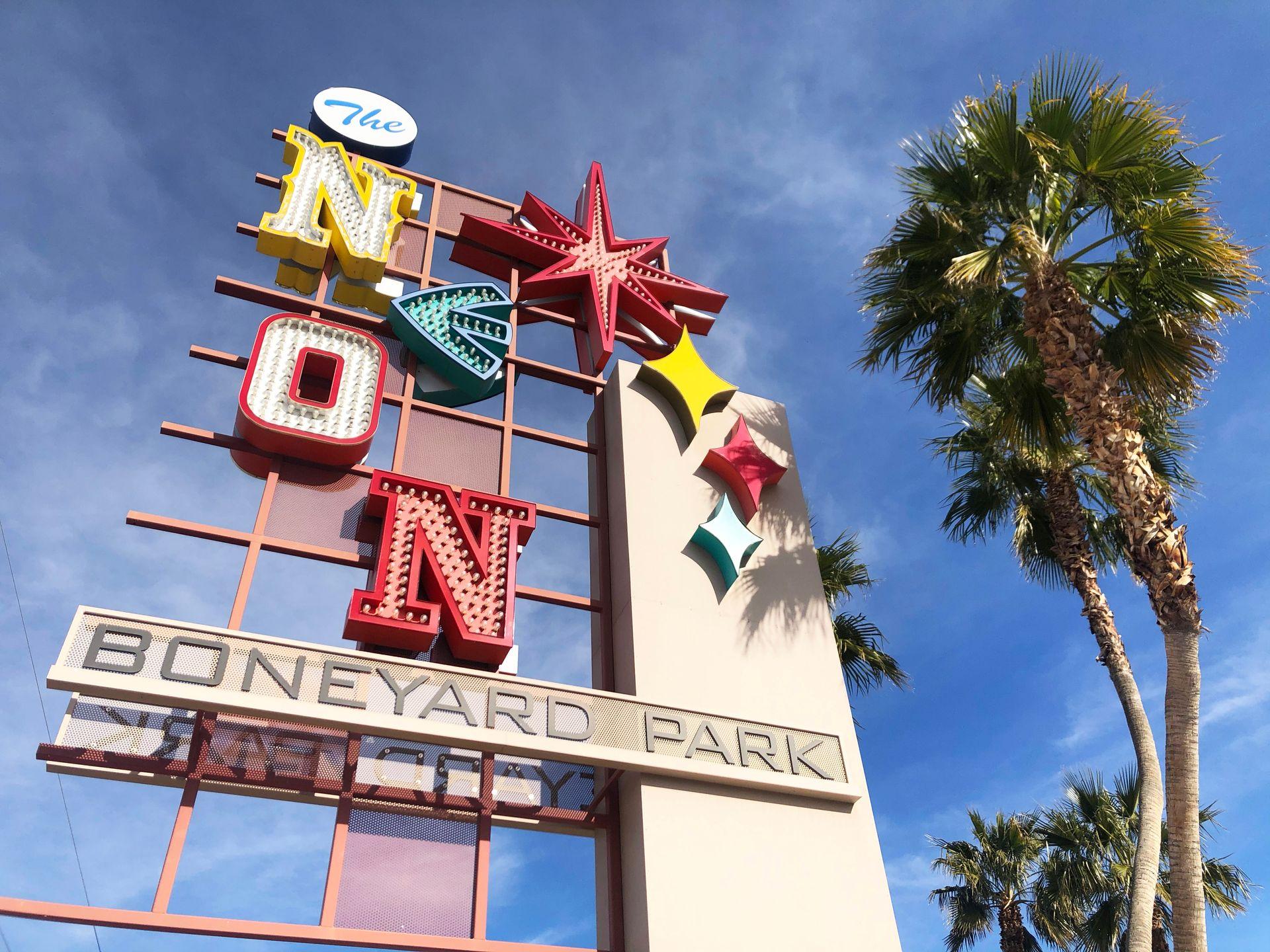 The sign for the Neon Museum next to a palm tree. It reads Neon Boneyard Park.