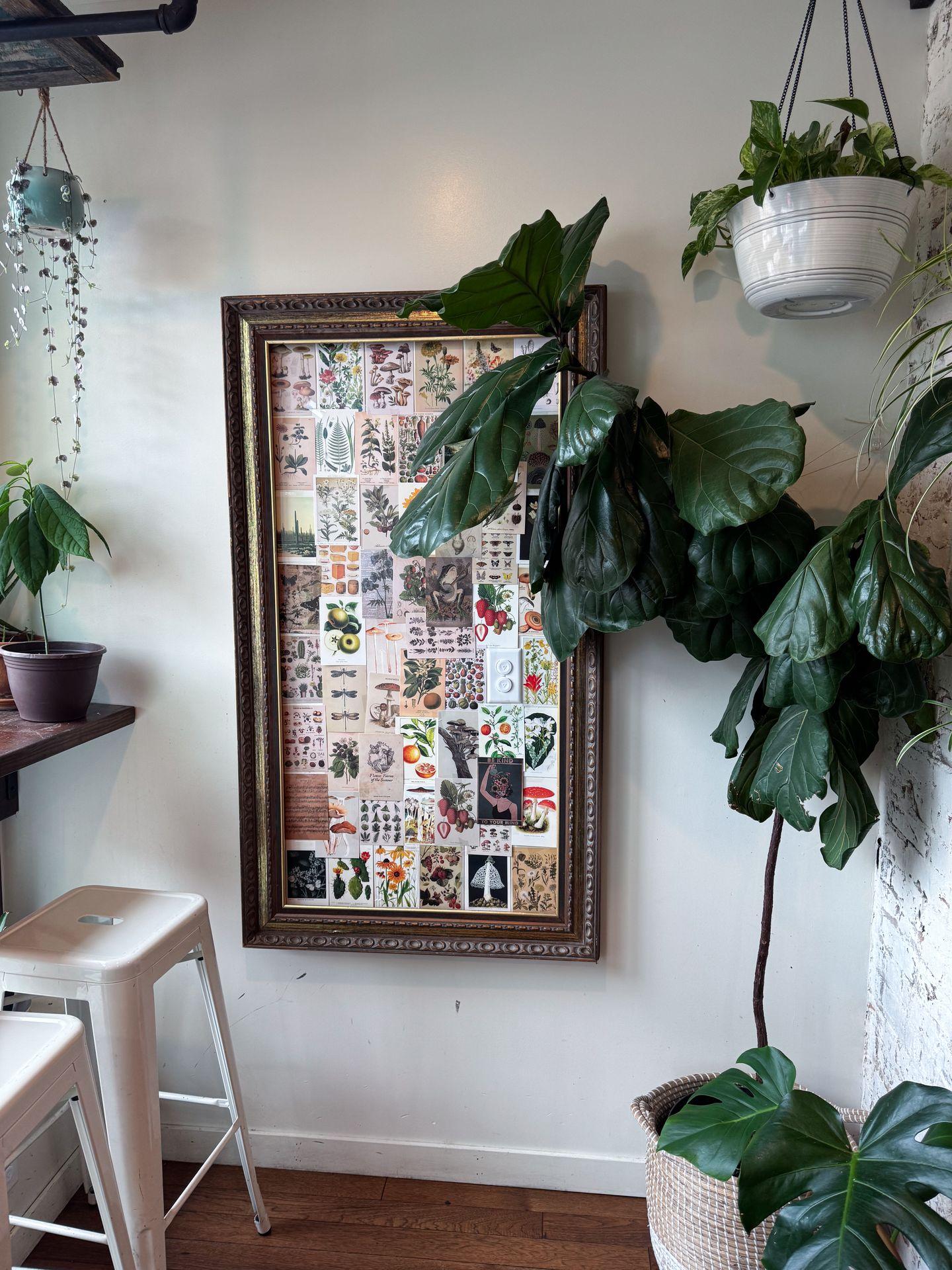 A large piece of artwork and some green plants inside of Greenhouse Cafe