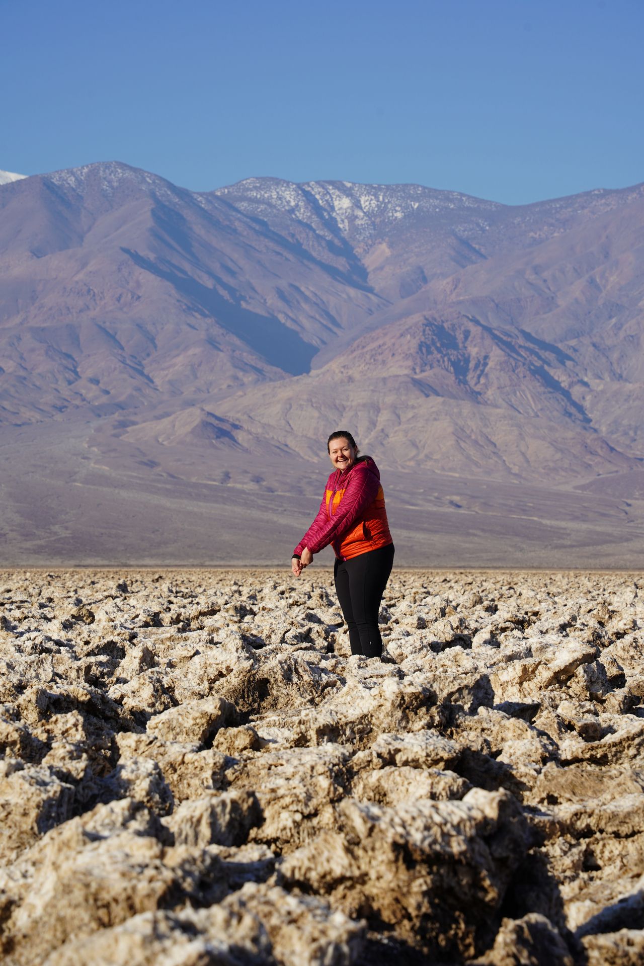 Lydia pretending to hold a golf club at the Devil's Golf Course in Death Valley. There are giant, white rock formations that resmble huge golf balls.
