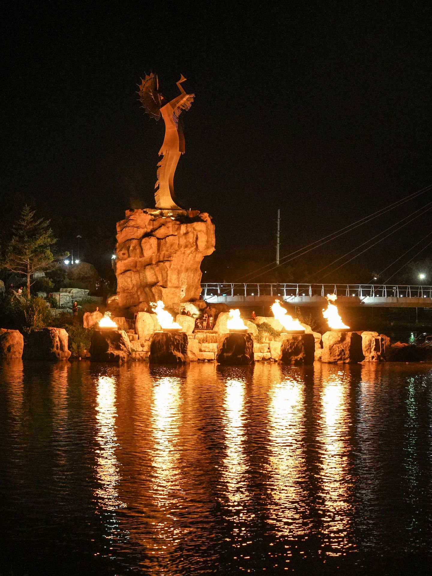 The Keeper of the Plains statue surrounded by fire pots at night