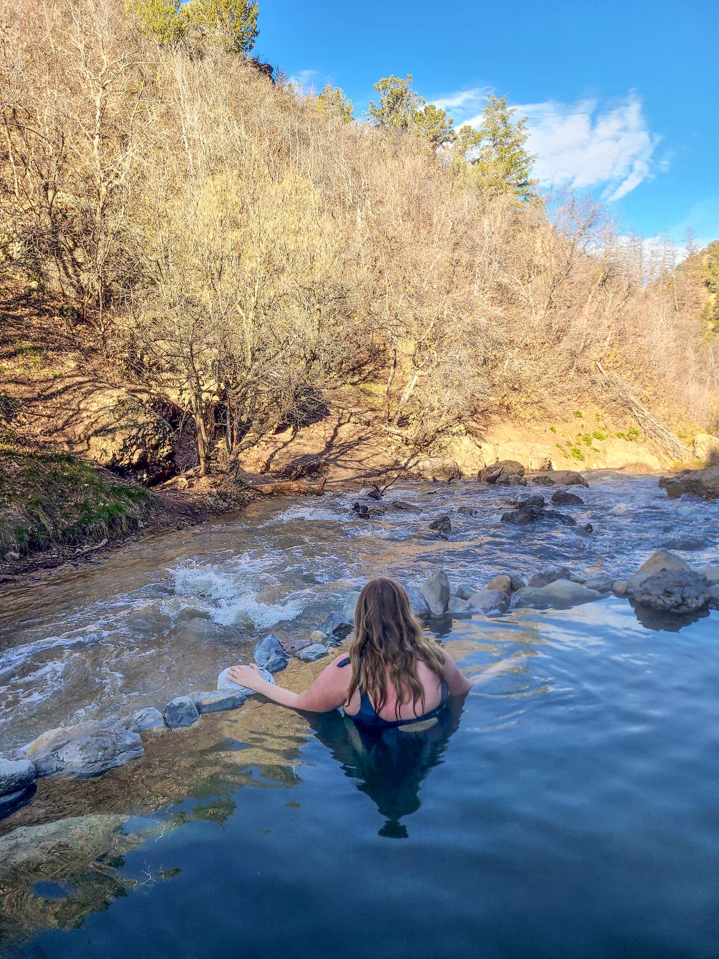 Lydia soaking in a hot spring pool looking out over the river