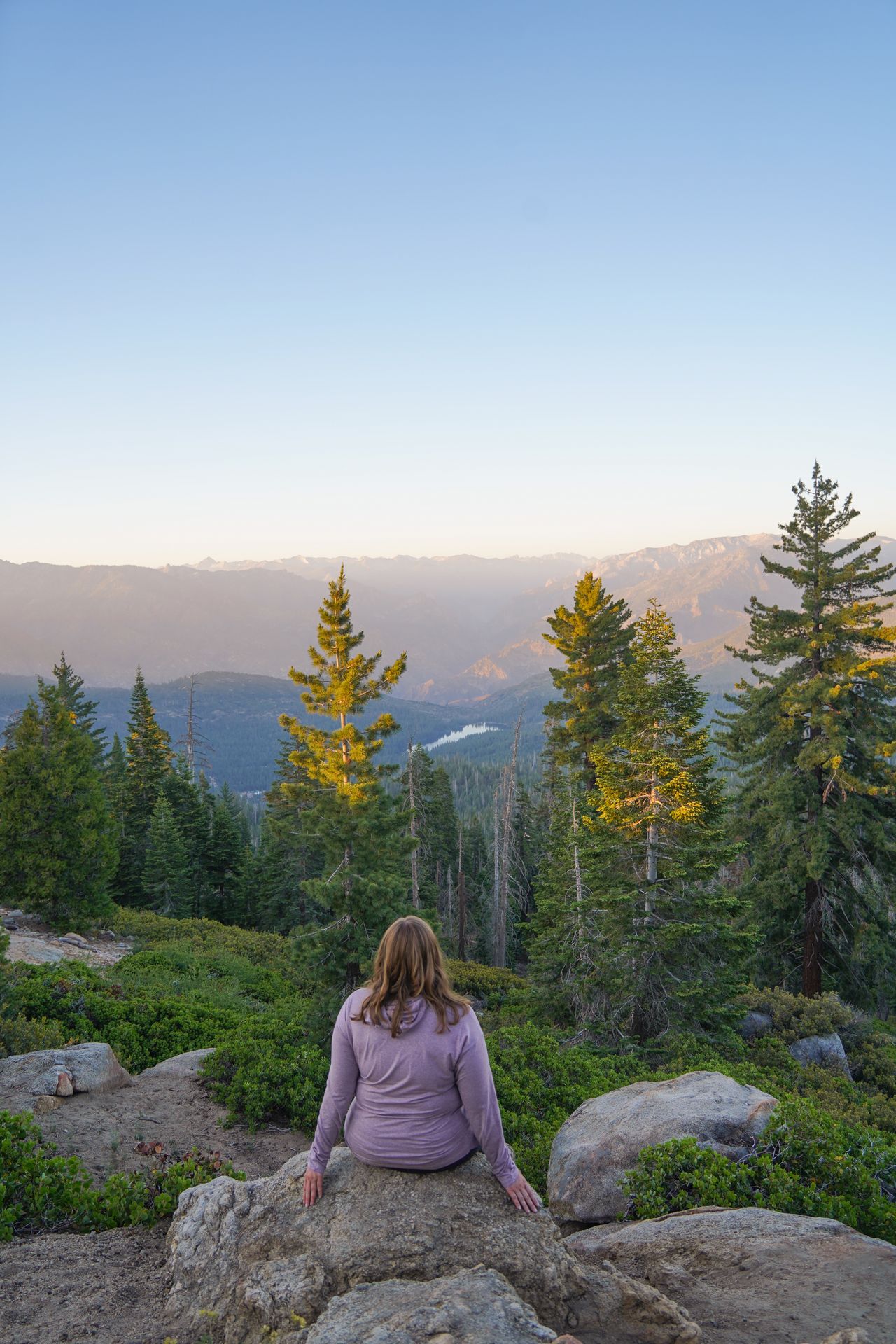Lydia sitting and admiring mountains and a distant lake from Panoramic Point in Kings Canyon