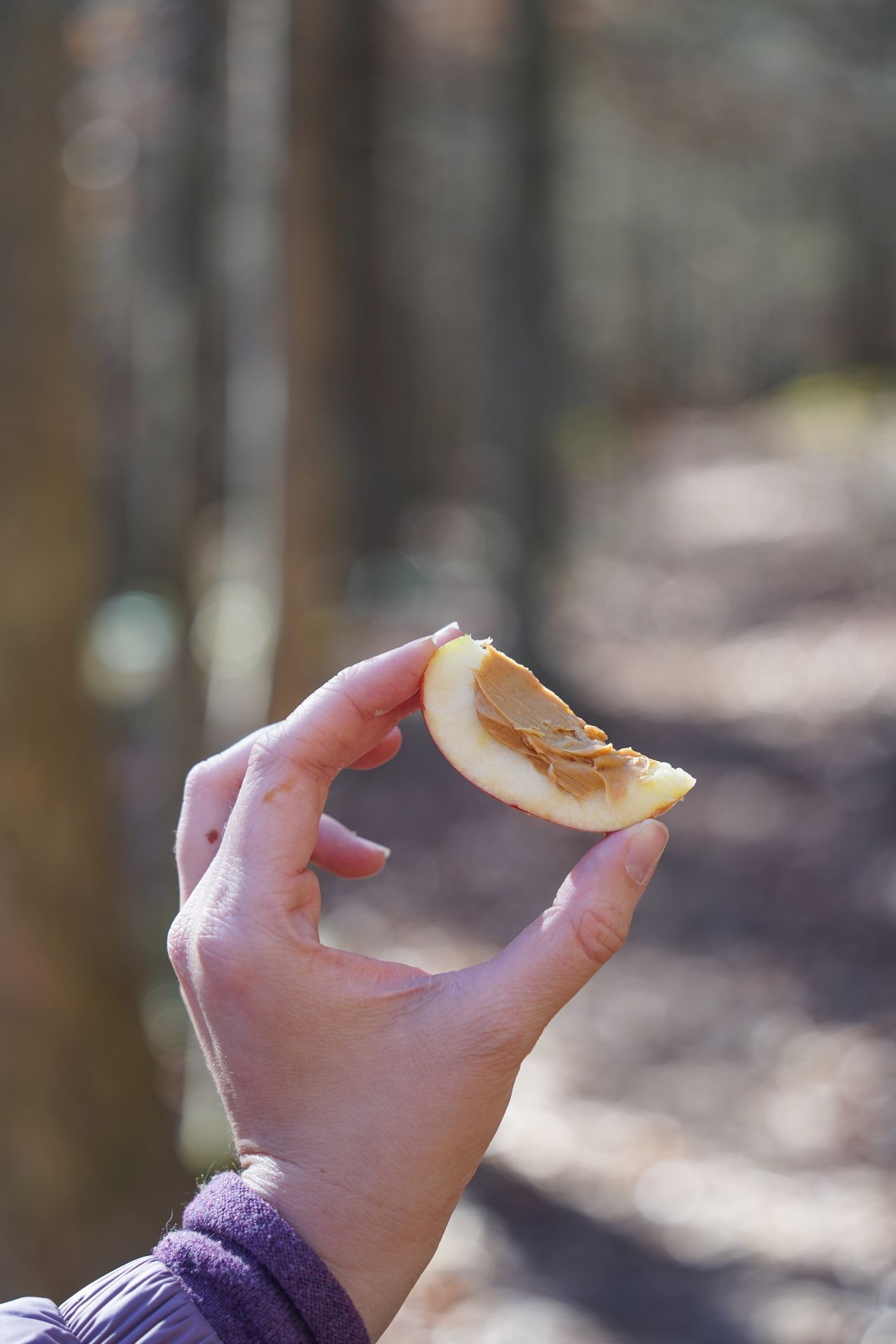 Holding up an apple slice with a bit of peanut butter on it.