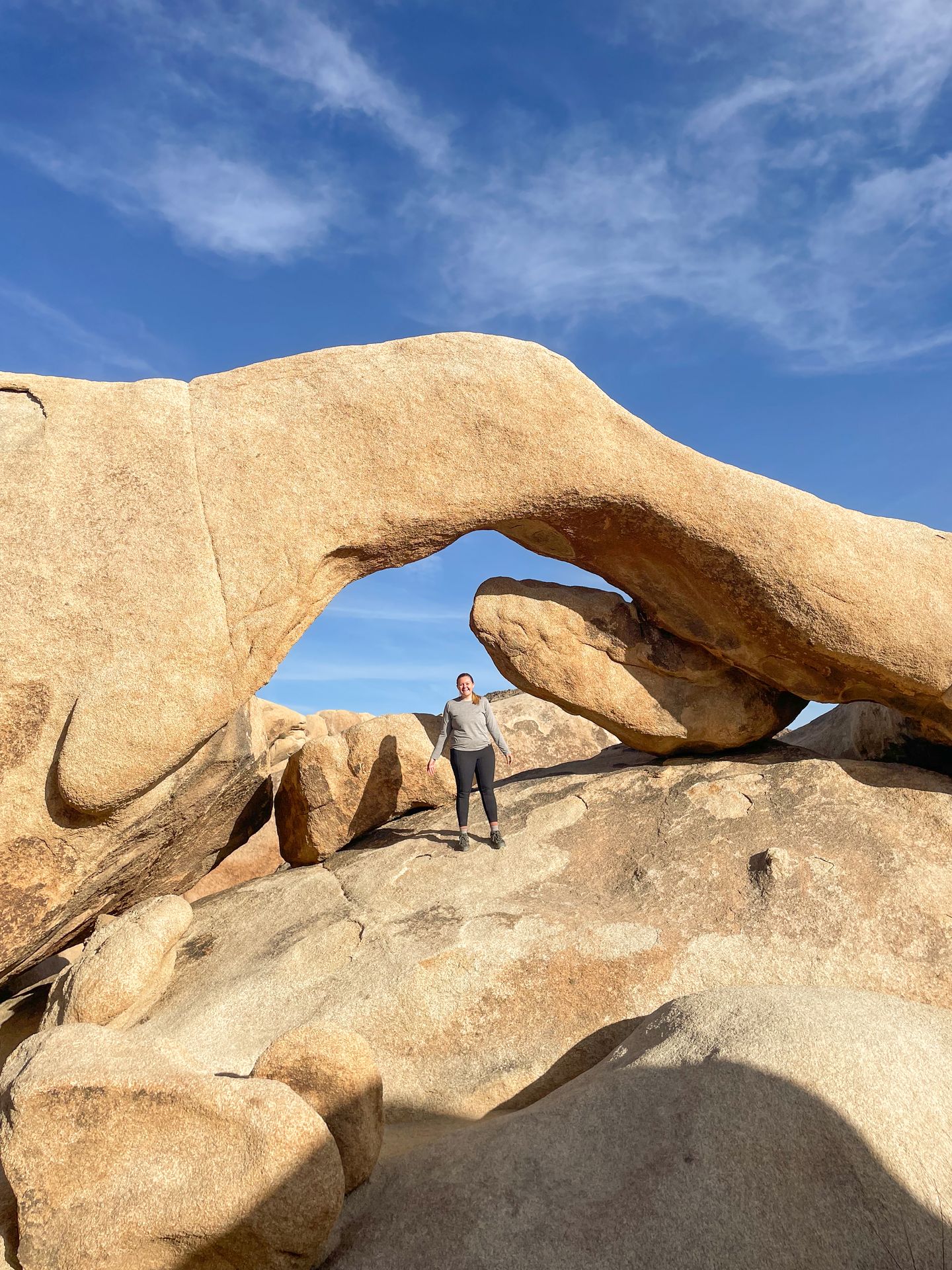 Lydia standing under an arch on the Arch Rock Trail in Joshua Tree.
