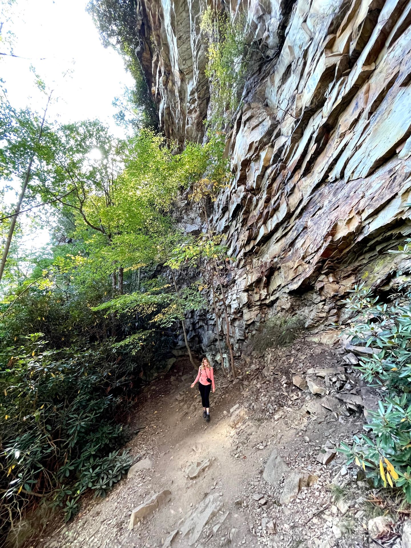 Lydia hiking on the Castle Rock trail. She stands next to a giant rock wall.