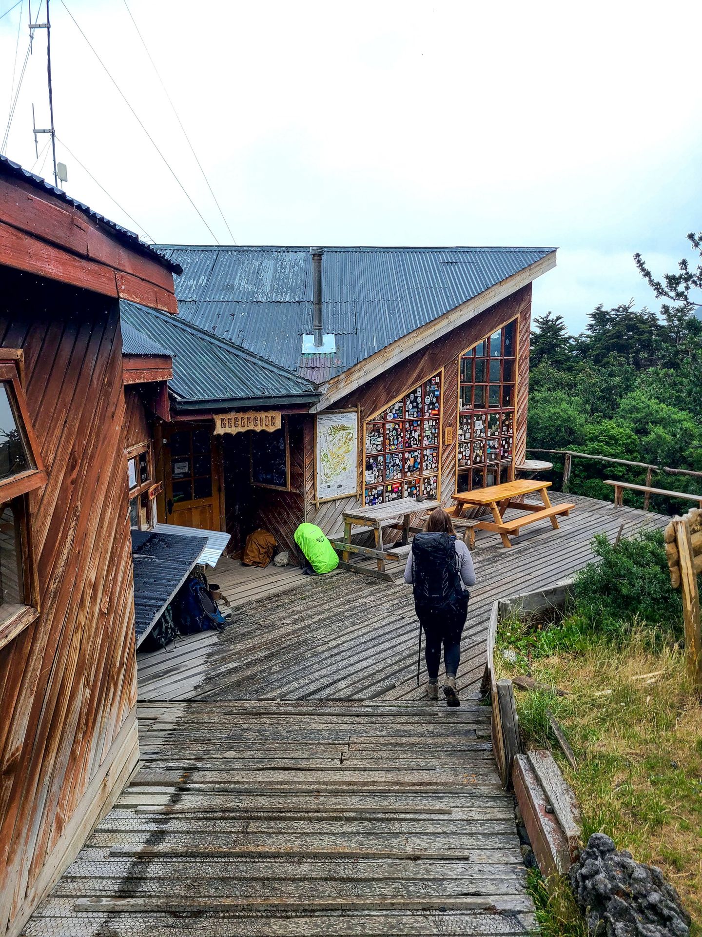 Lydia hiking up the entrance of Los Cuernos. The building is wooden with an angled roof and has stickers on the window.