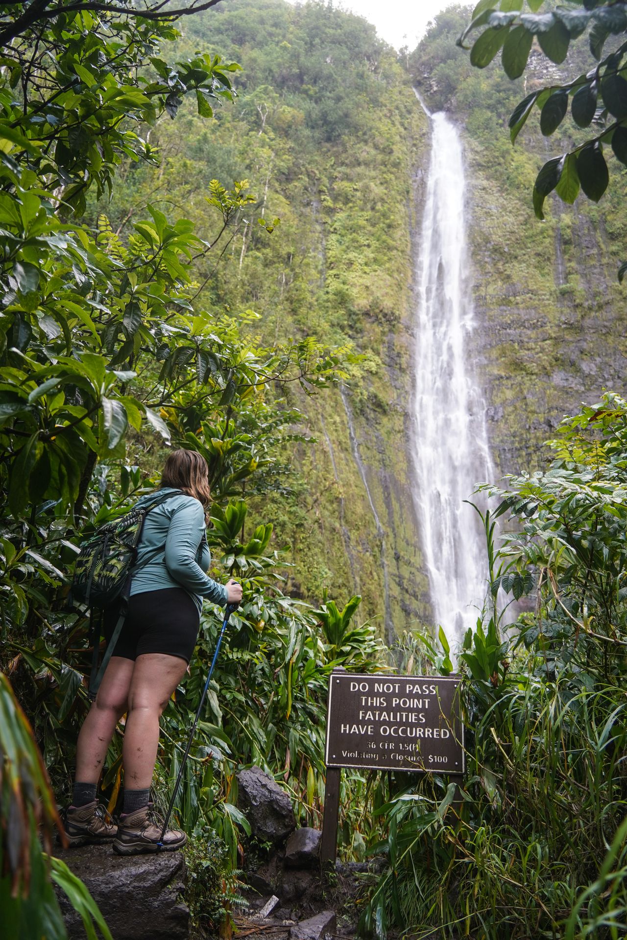 Lydia standing next to a sign that reads do not pass in front of Waimoku Falls in Haleakala National Park