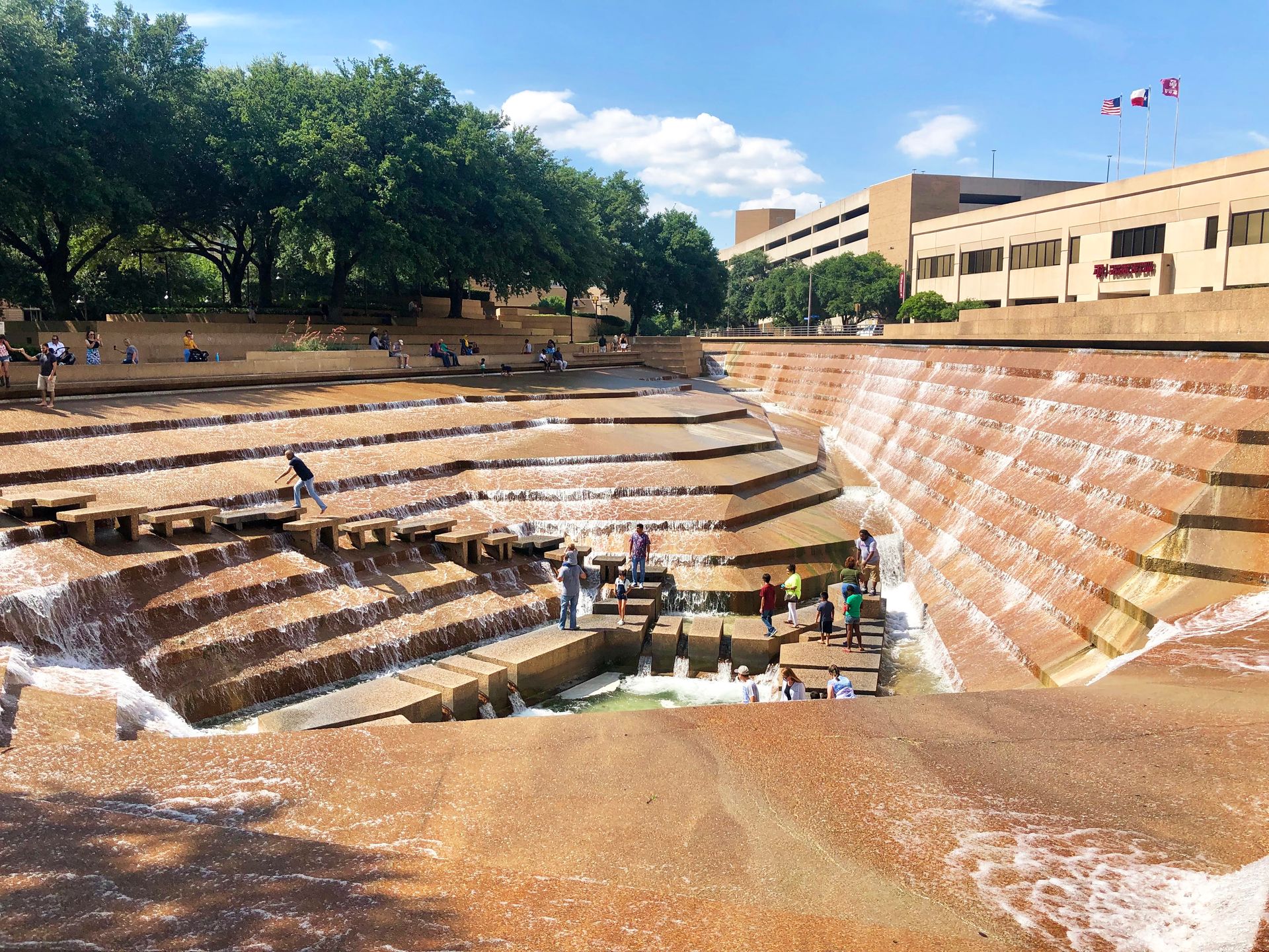 A large fountain area with steps leading down to the center. There are people walking across the various steps.
