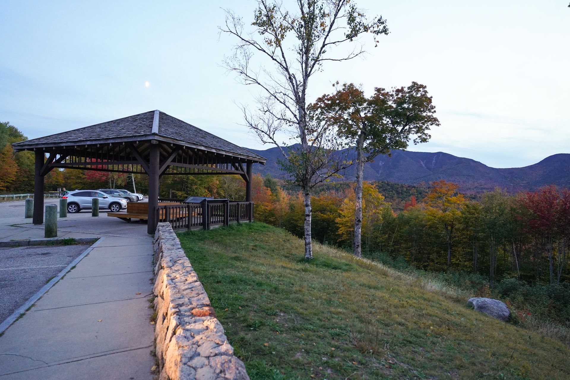 A gazebo next to a parking area and a view of mountains in the distance