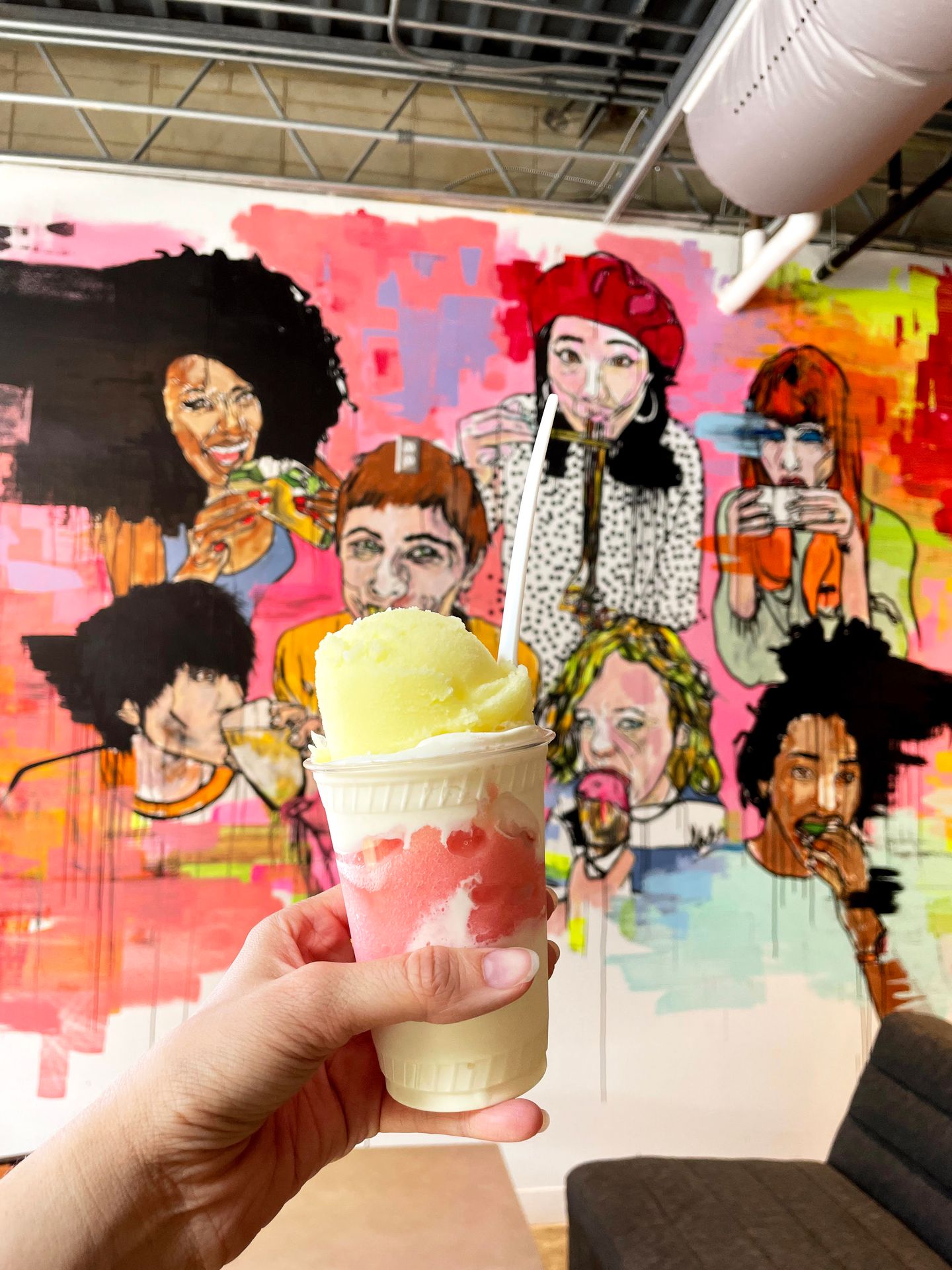 Holding up a cup layered with frozen custard and strawberry and lemonade italian ice.