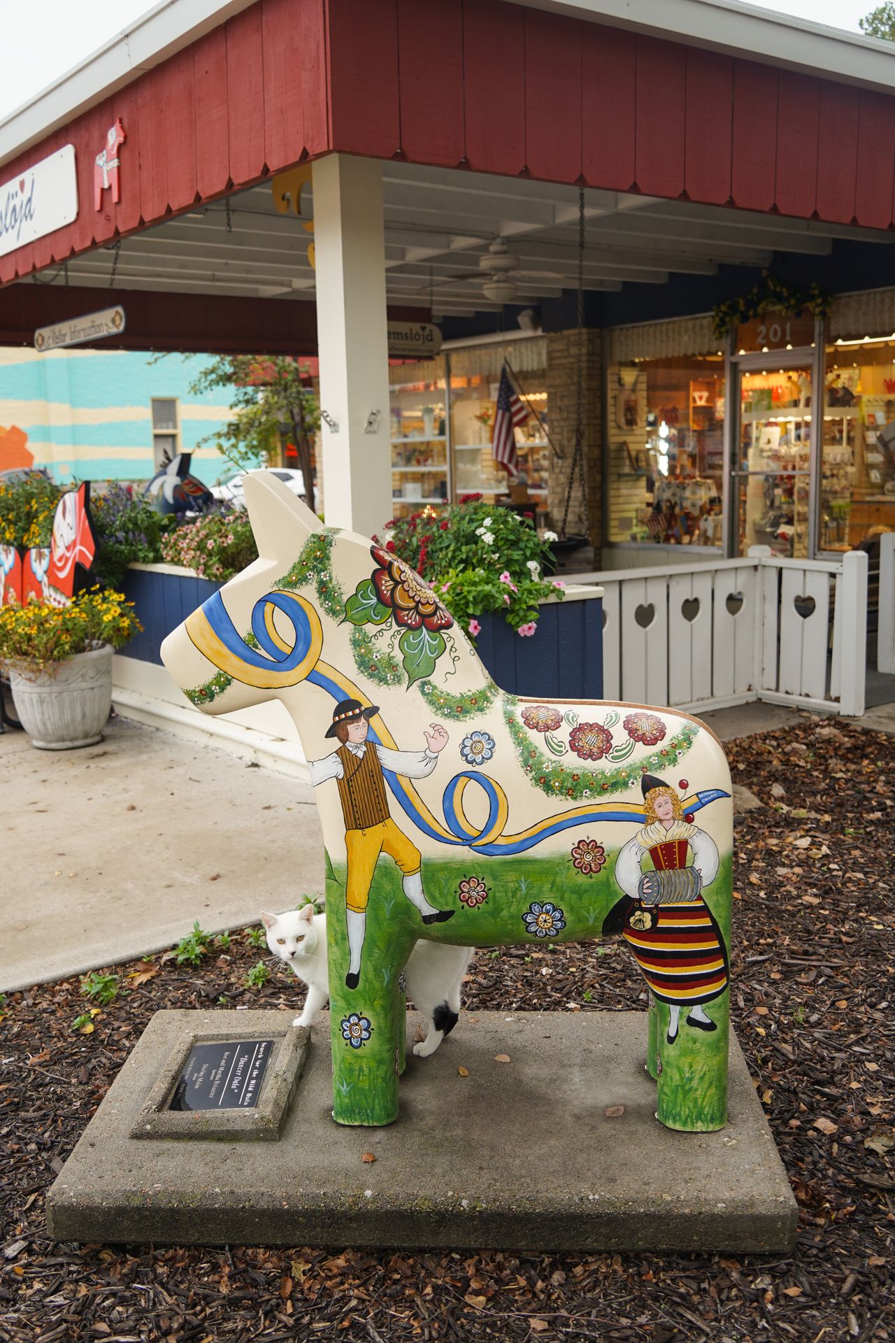 A painted dall horse with Swedish scenes in front of a Swedish store in Lindsborg