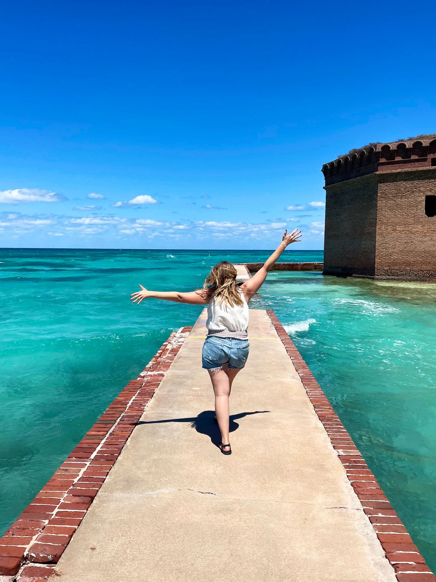 Lydia walking away with her hands in the air on the moat wall at Dry Tortugas
