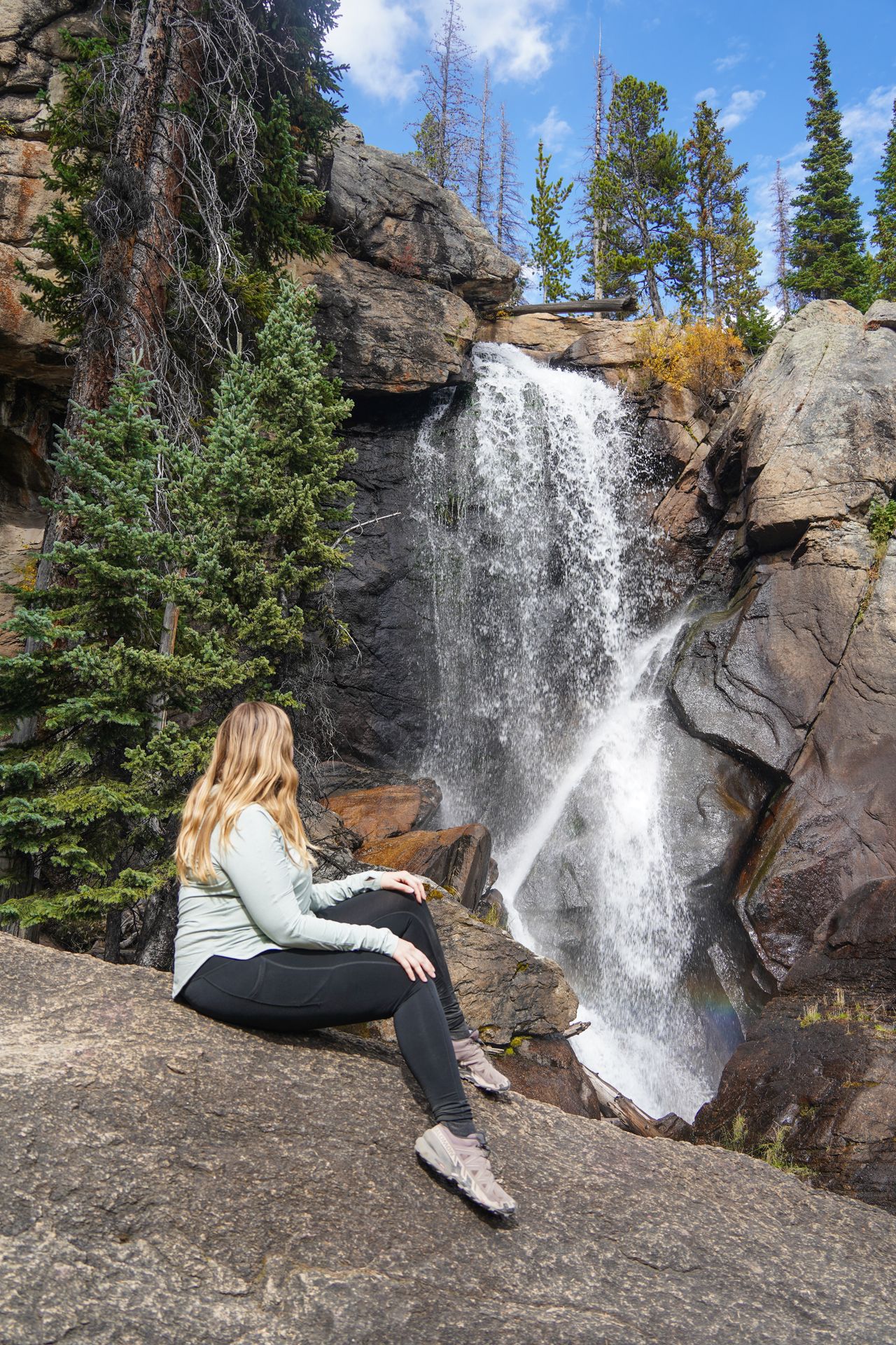 Lydia sitting on a boulder and looking at a waterfall