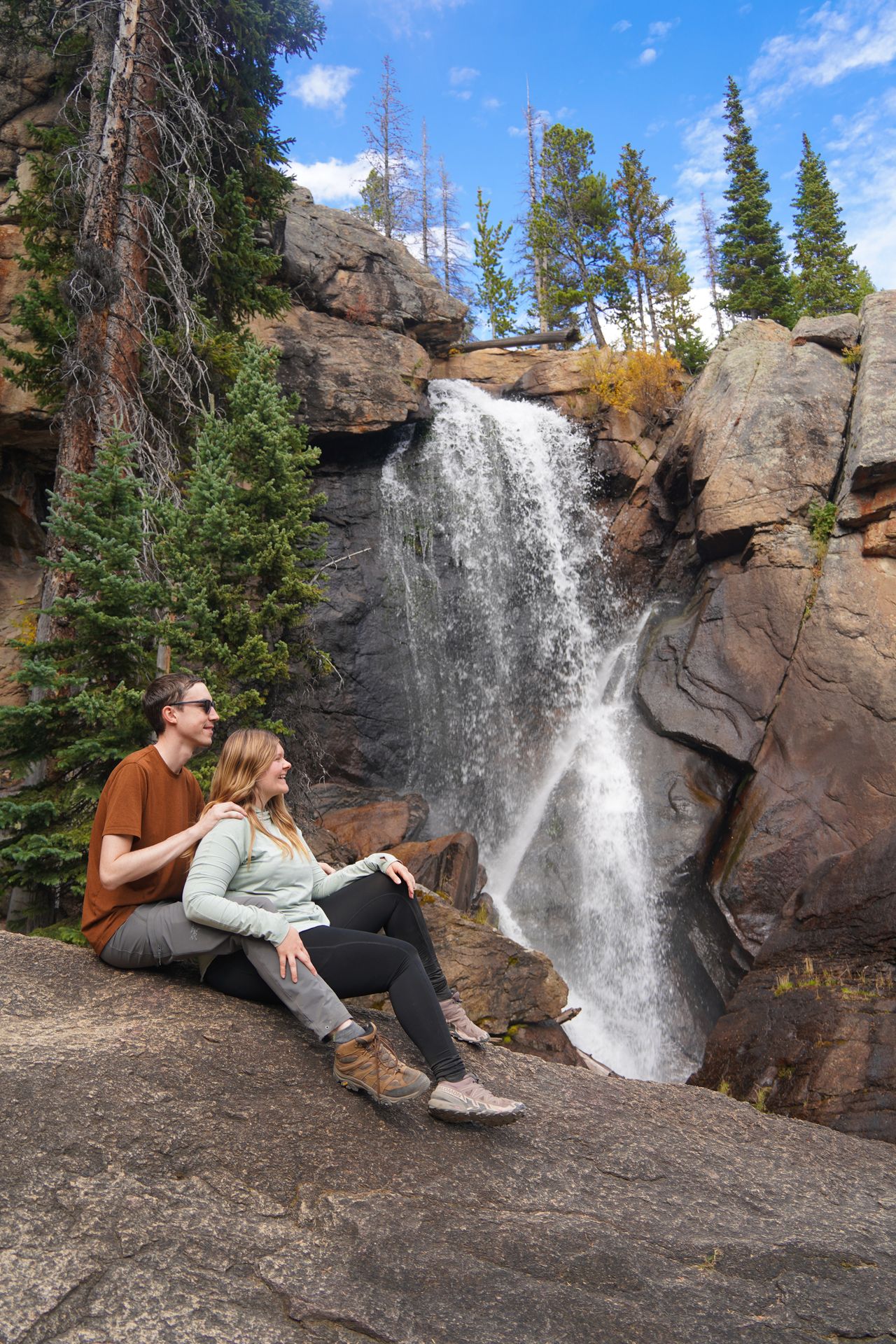 Lydia sitting on a boulder and looking at a waterfall