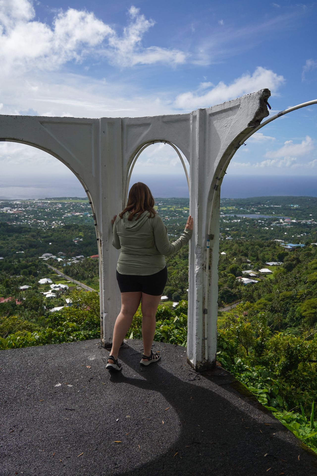 Lydia standing below an arch and looking out to a view