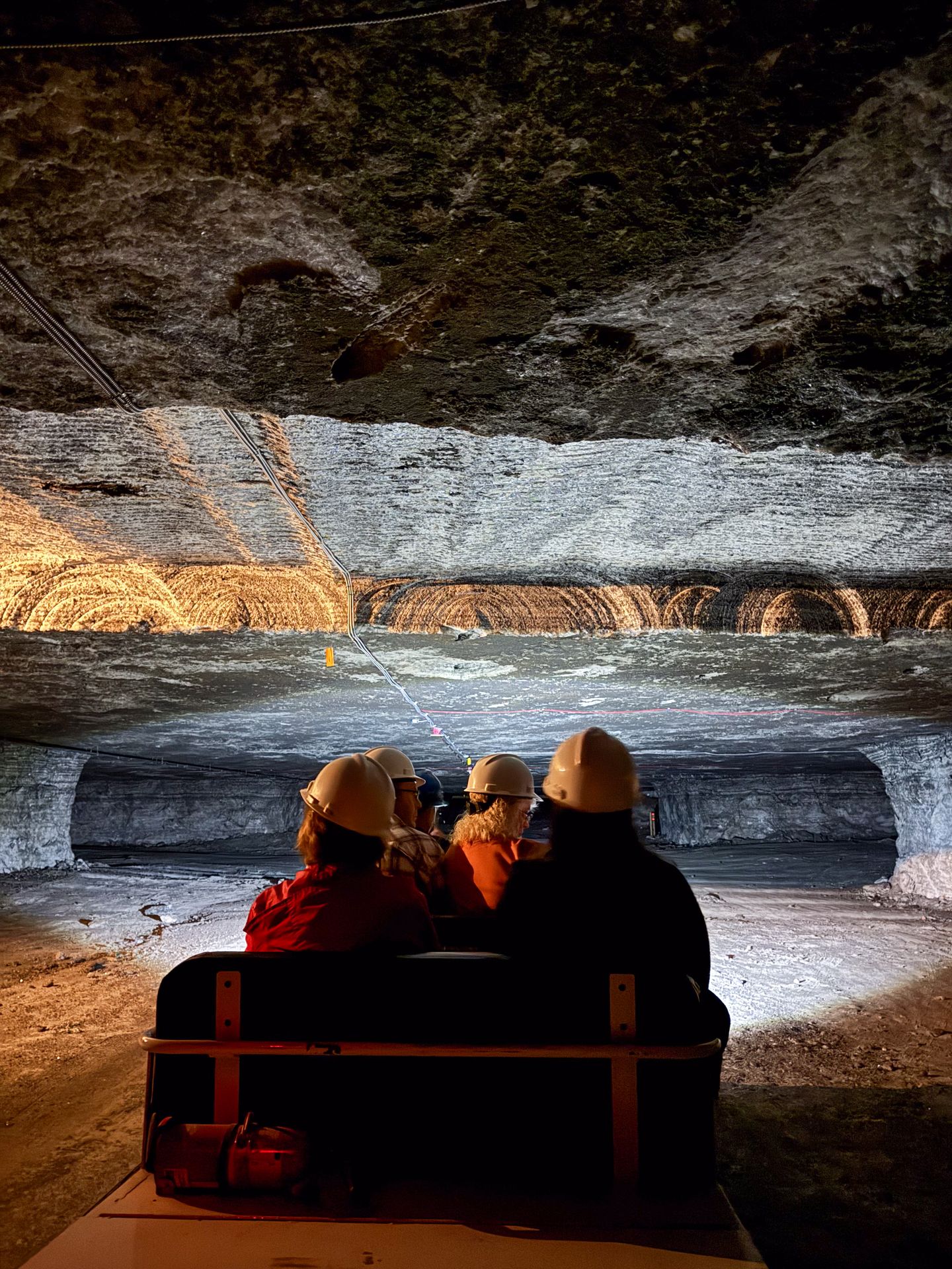A view of riders wearing helmets on a train in the underground salt tunnels at Strateca