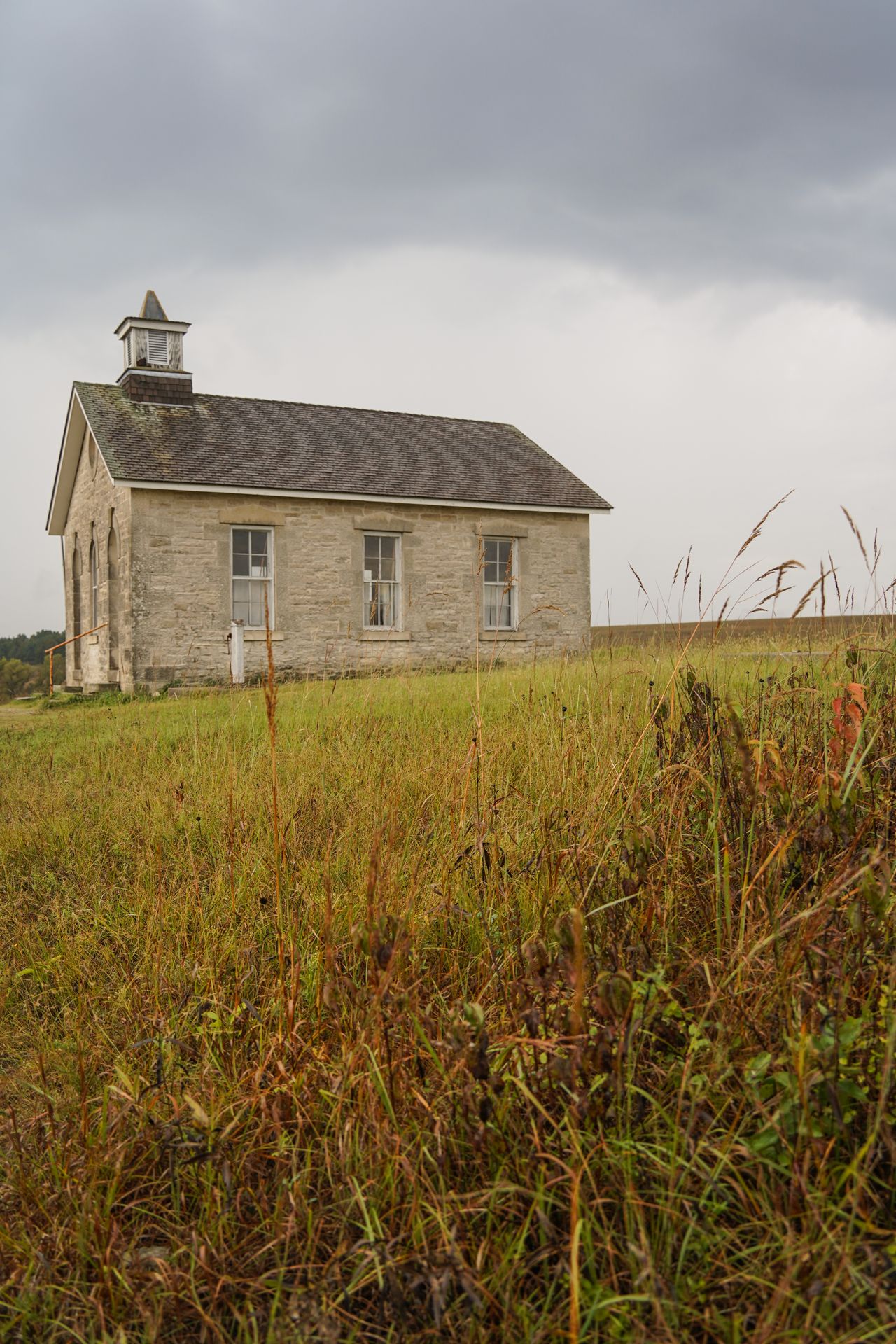 A historic schoolhouse with tallgrass in the foreground