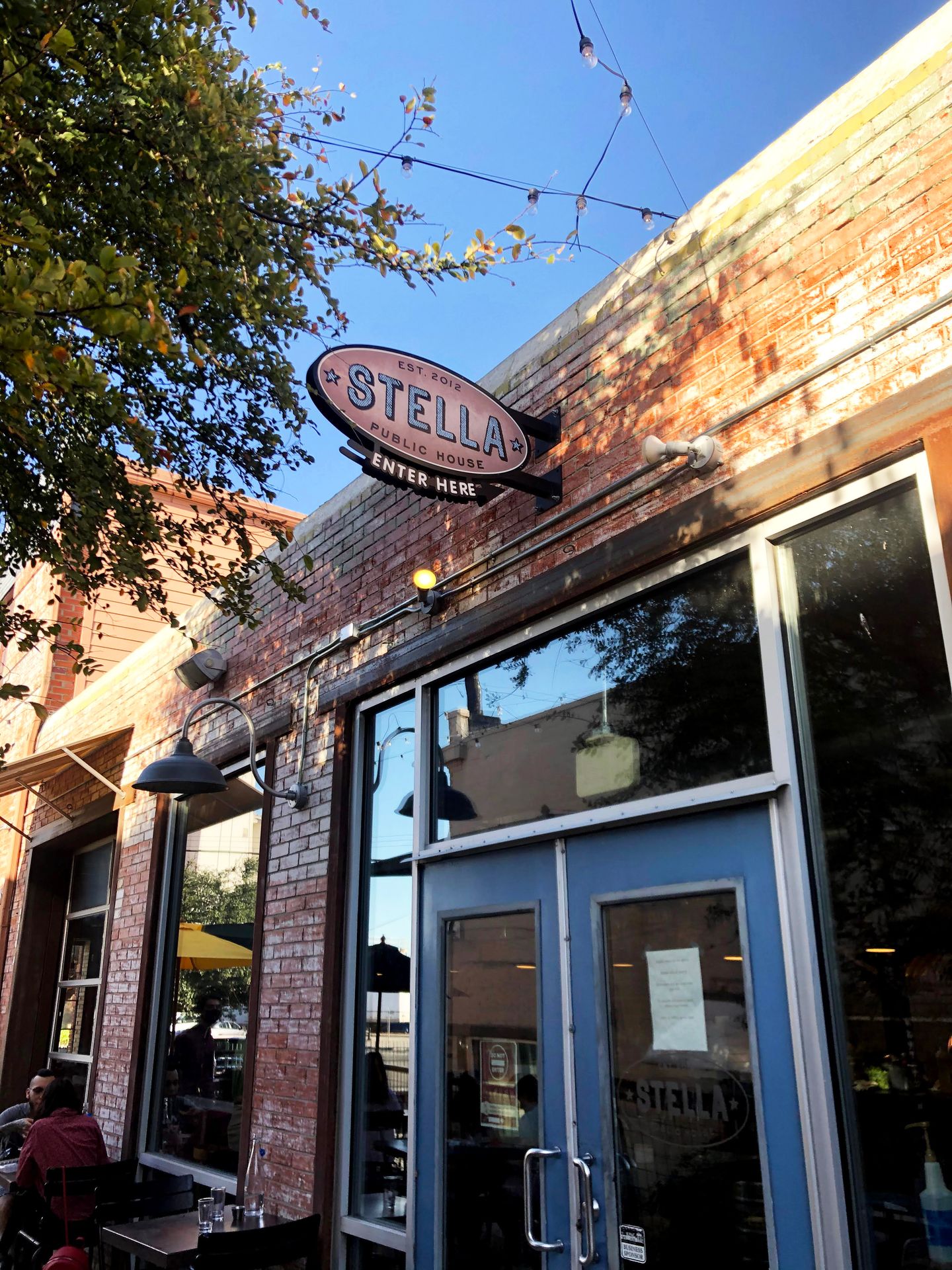 The exterior of Stella Public House. There is a brick building with a blue door.