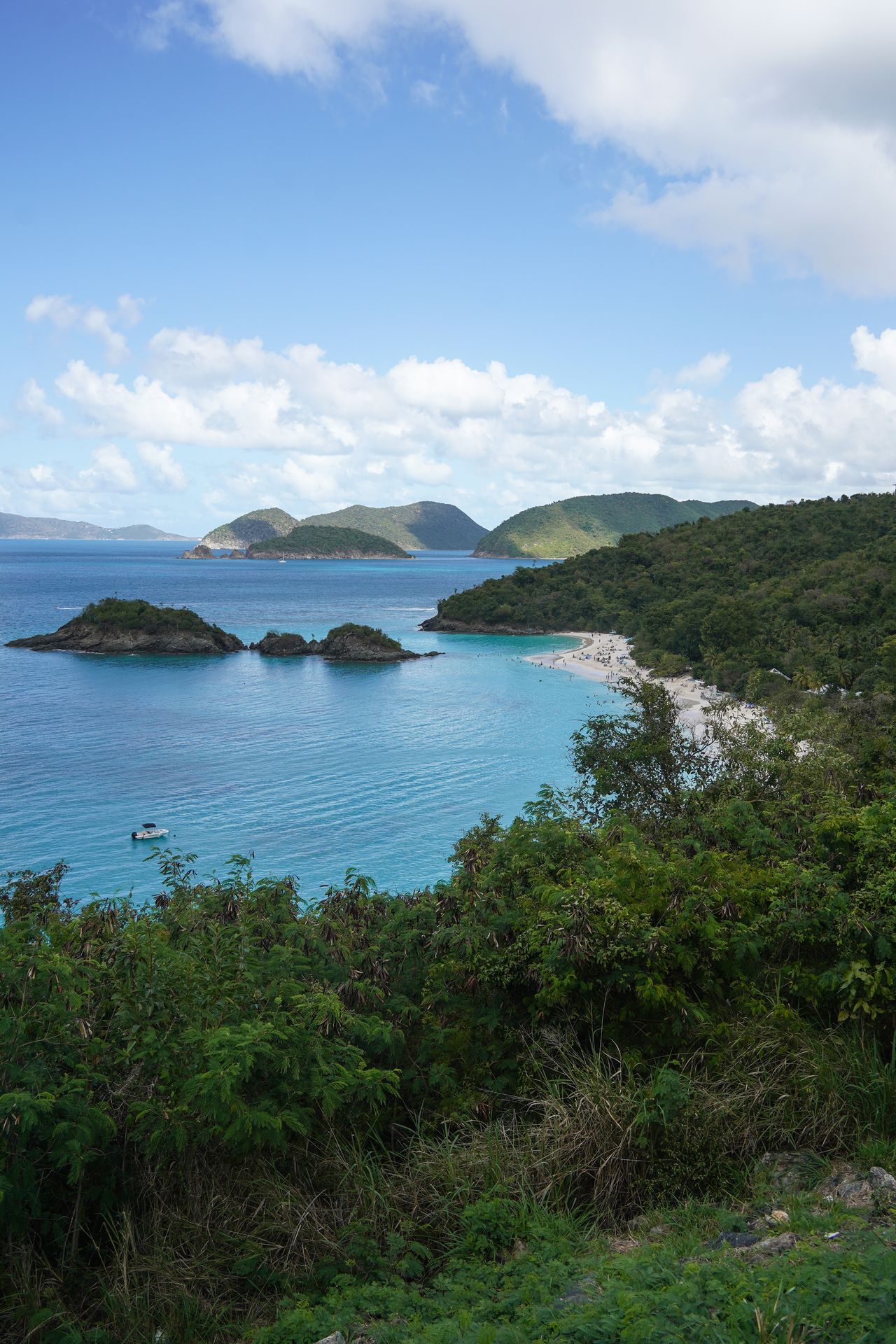 An overlook of a bay and a white sand beach with a couple small islands near the shore