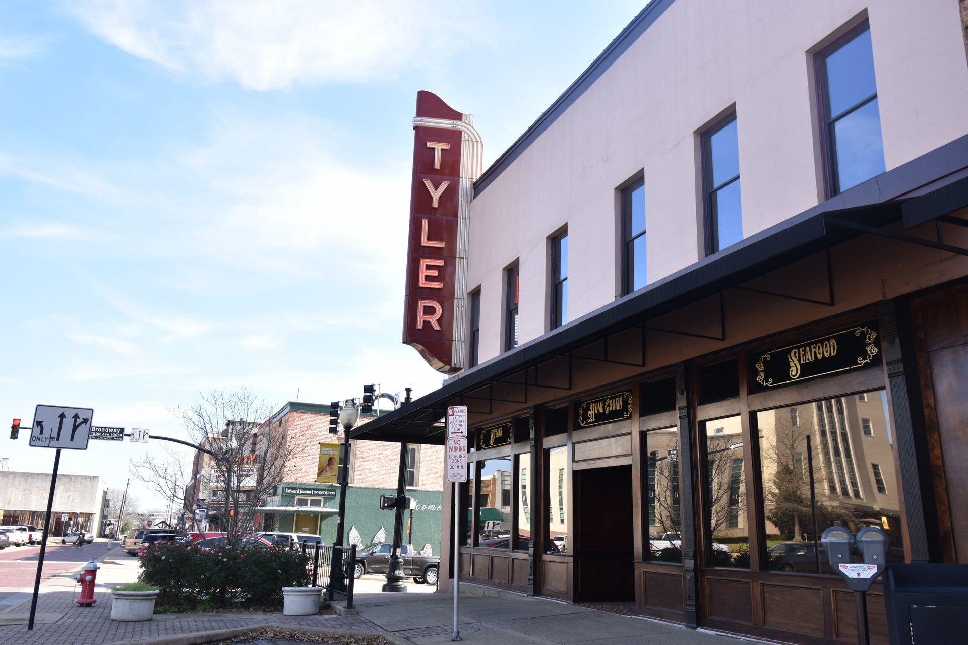 The exterior of a building in downtown Tyler. The building is pink and there is a red sign that reads Tyler.