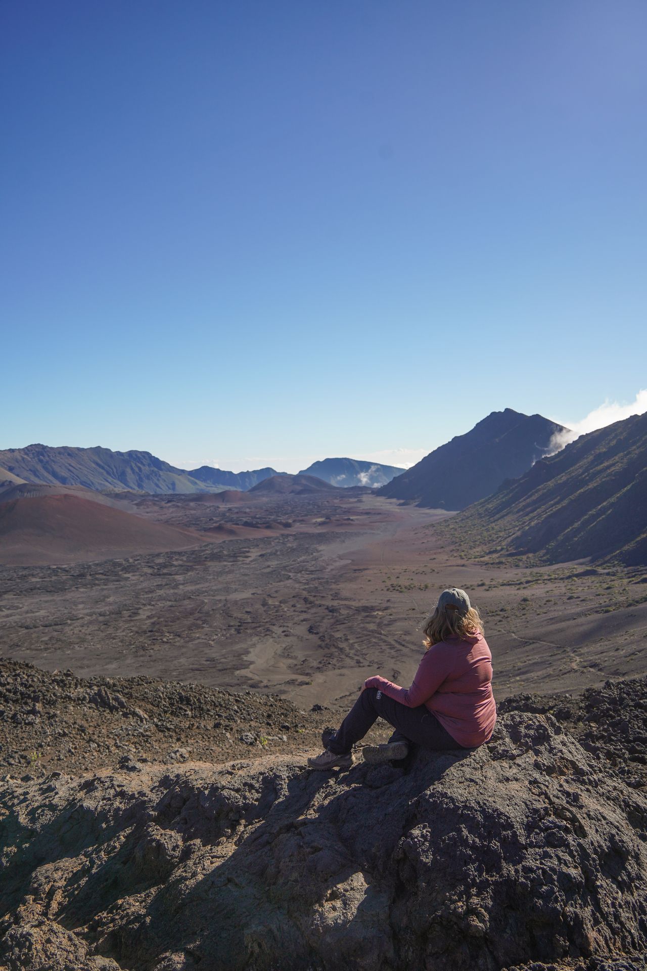 Lydia sitting on a rock and looking out a crater of Haleakala