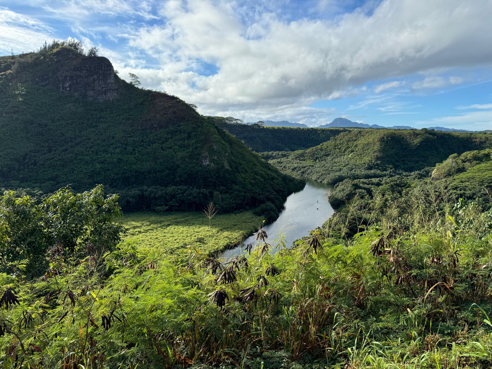 An overlook of the Wailua River, which flows next to a green mountain