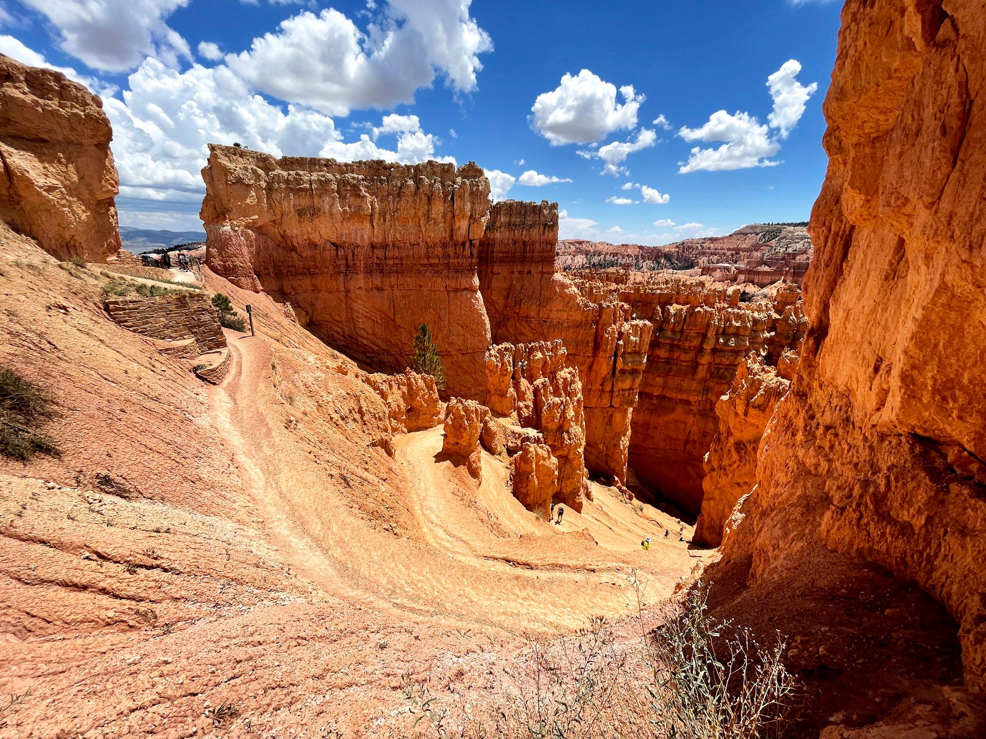An area of swithbacks leading to the bottom of the canyon in Bryce Canyon. The switchbacks are framed by tall, orange rock formations.